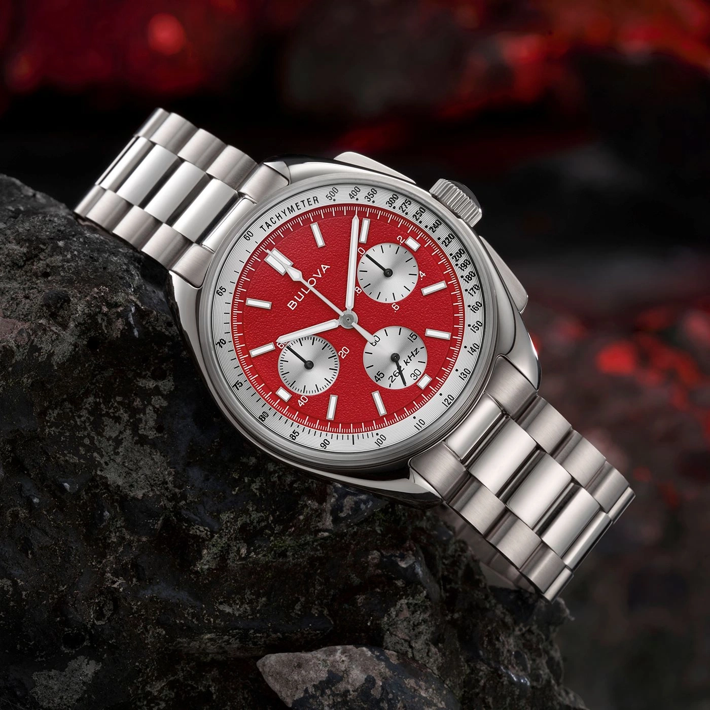 Rote Bulova-Uhr mit silbernem Armband auf einem dunklen Stein, Tachymeter.