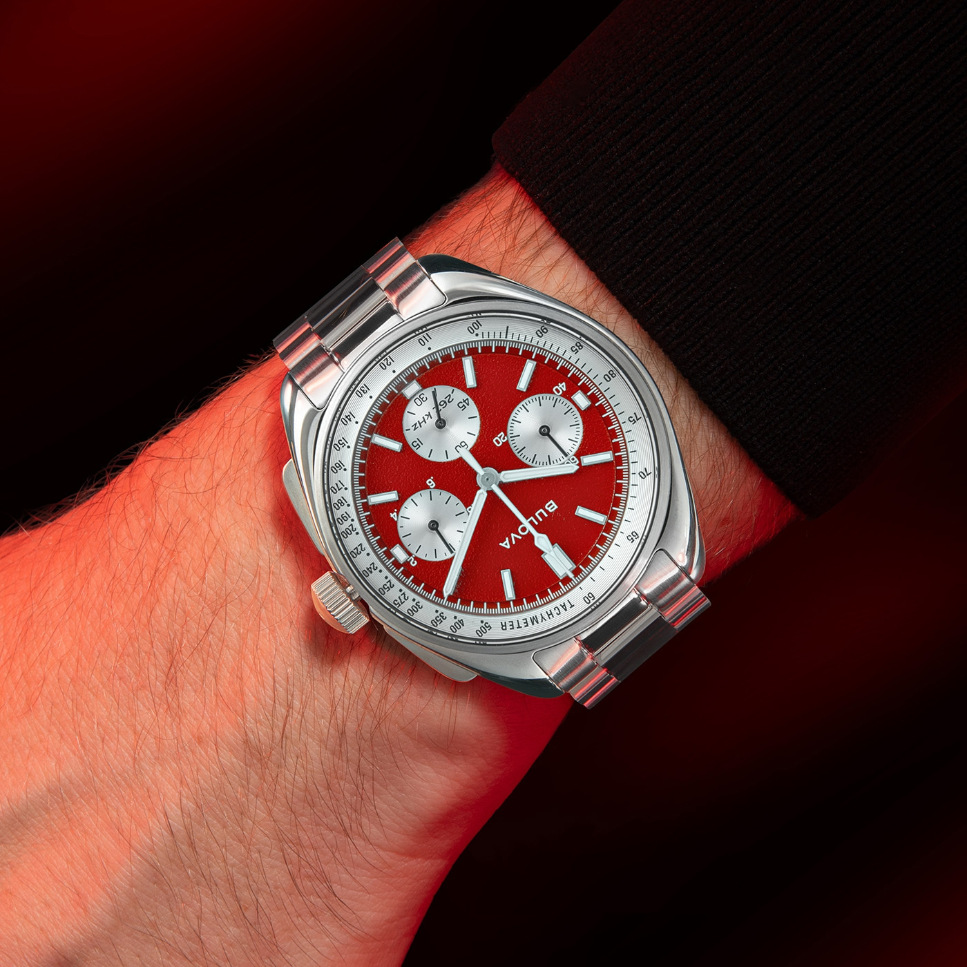 Uhr am Handgelenk mit rotem Zifferblatt und silbernem Armband, Bulova.