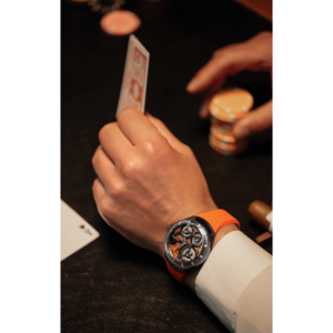 Mann mit Uhr spielt Poker, hält Karten und Chips in der Hand.