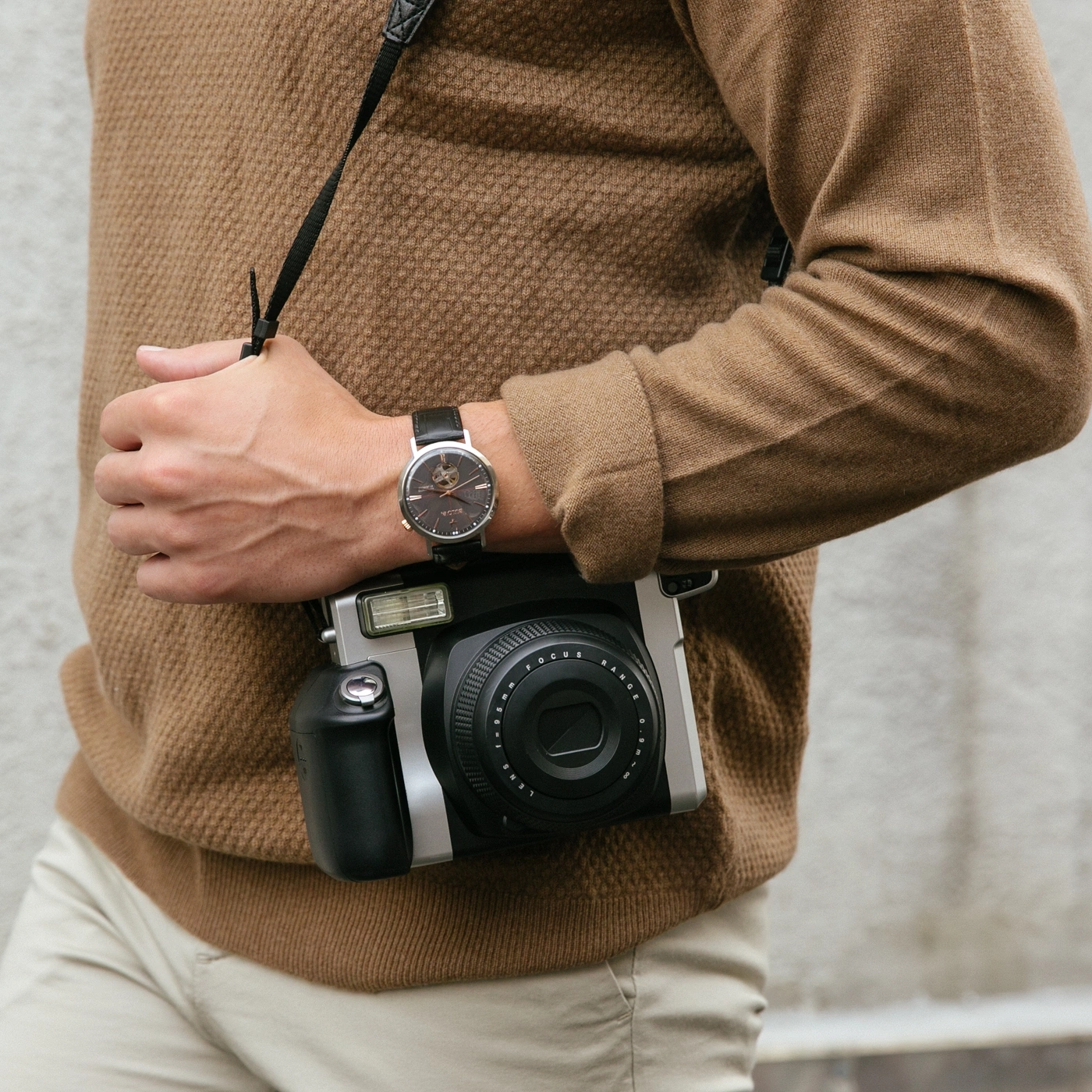 Mann mit Uhr und Kamera, brauner Pullover, beige Hose, Nahaufnahme, Mode