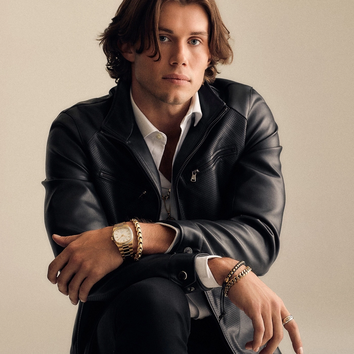 Mann mit Lederjacke, Uhr und Schmuck, posiert selbstbewusst
