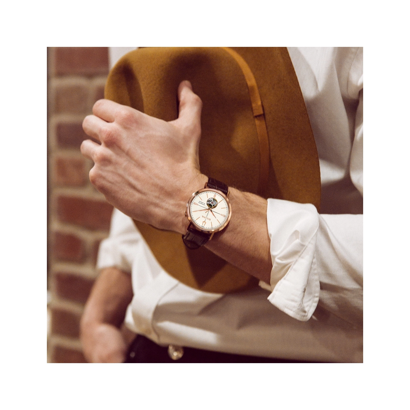 Mann mit Uhr und Hut, der sich an einem Backstein lehnt