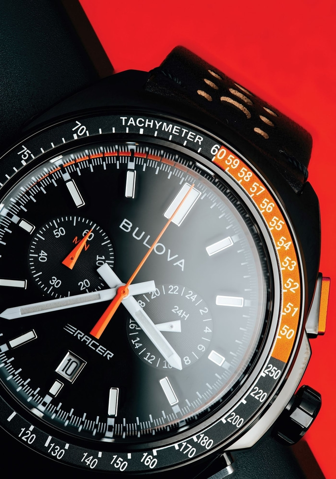Bulova-Uhr mit schwarzem Zifferblatt, Tachymeter-Skala und orangefarbenen Akzenten. Detailaufnahme.