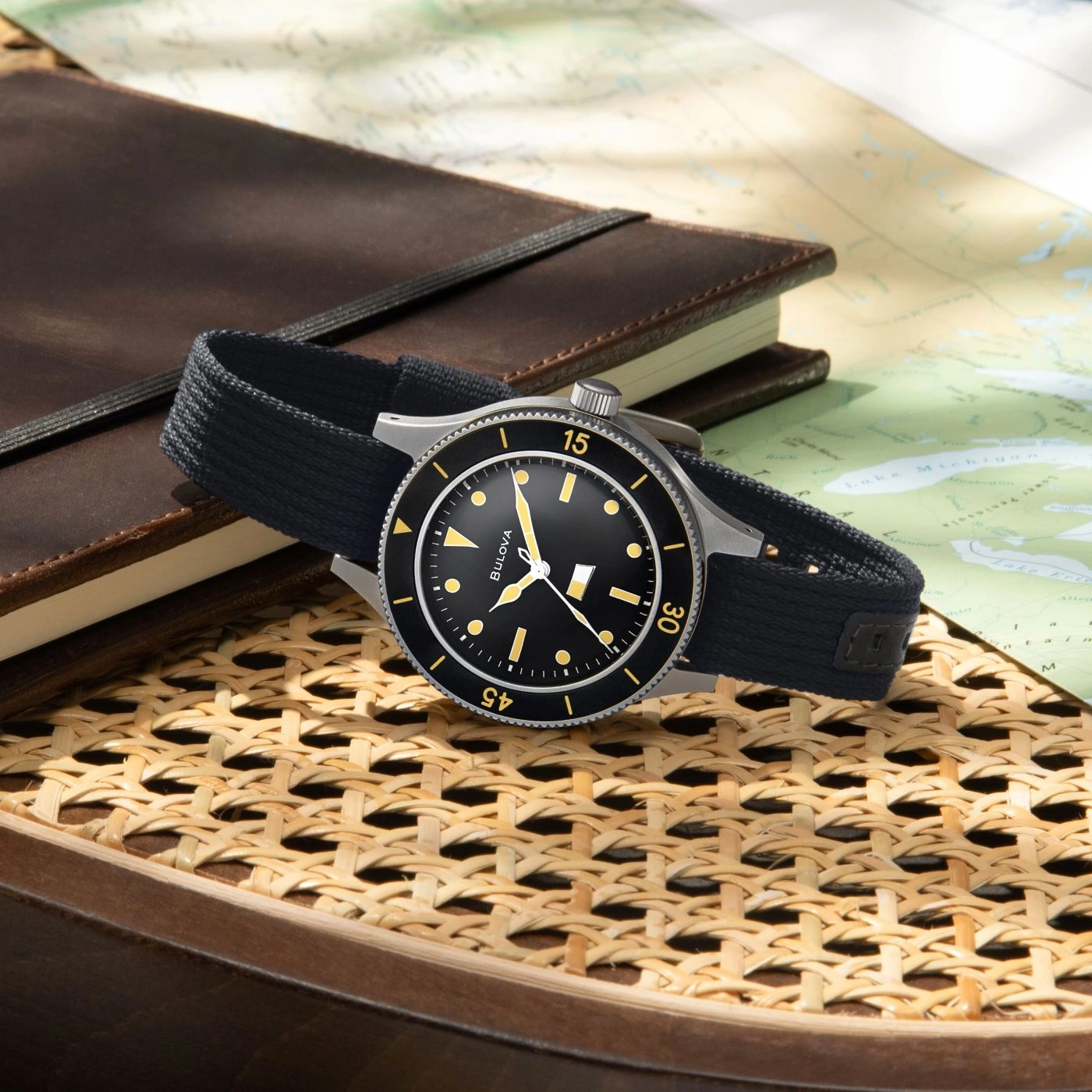 Uhr mit schwarzem Zifferblatt und Armband auf einer Karte und einem Notizbuch