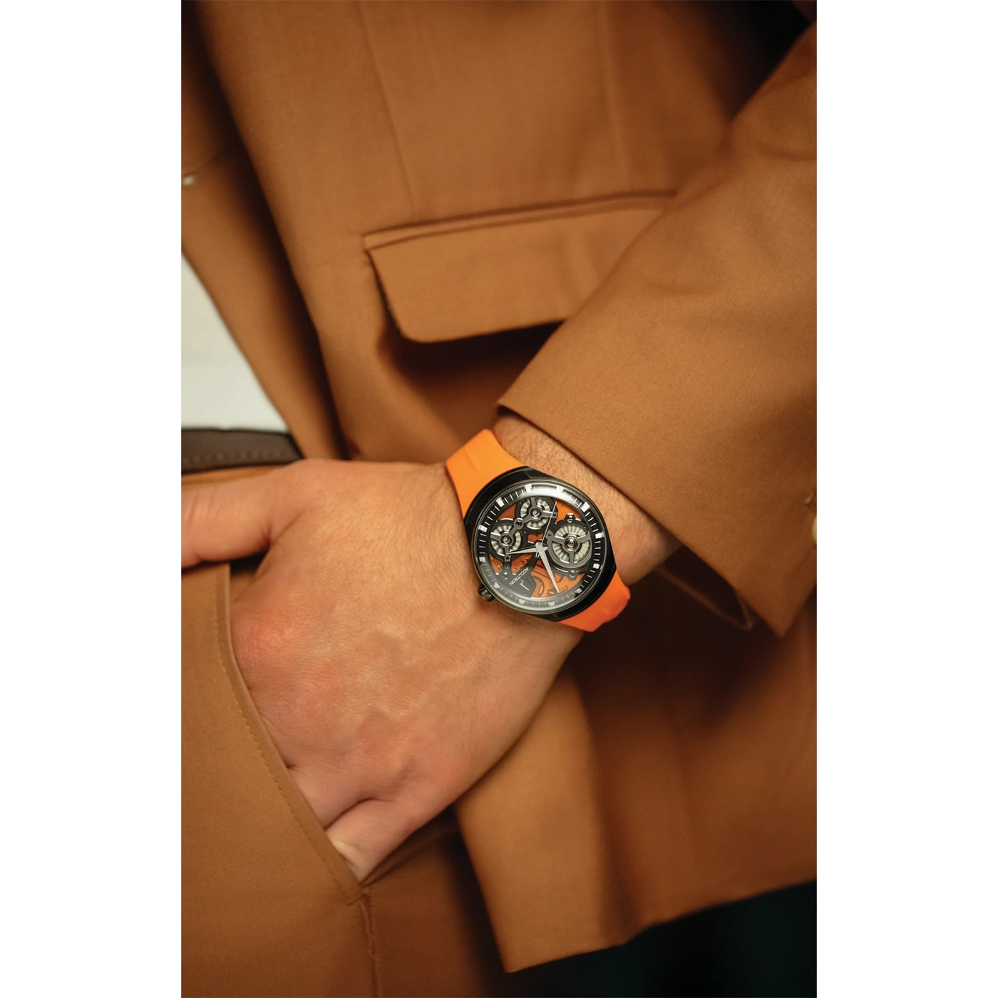 Mann mit Uhr und orangefarbenem Armband in brauner Jacke