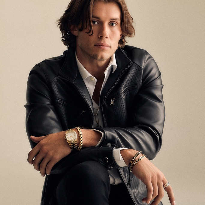 Mann mit Lederjacke, Uhr und Schmuck, posiert selbstbewusst
