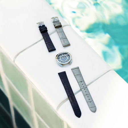 Uhr mit Armbändern auf weißer Oberfläche am Pool. Nahaufnahme.