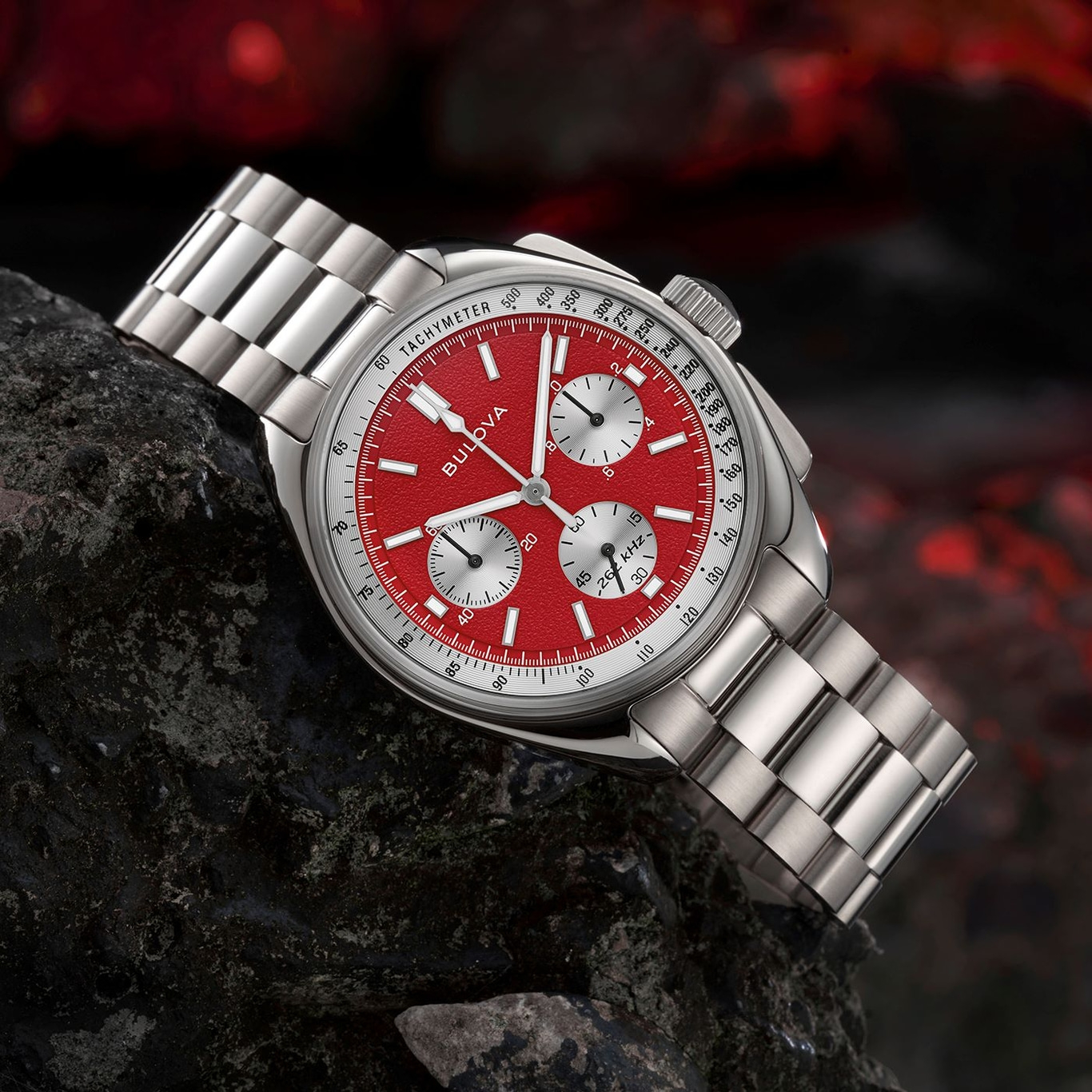 Rote Bulova-Uhr mit silbernem Armband auf einem dunklen Stein, Tachymeter.