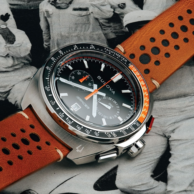Eine Bulova-Uhr mit schwarzem Zifferblatt und orangefarbenem Armband auf einem Hintergrund.
